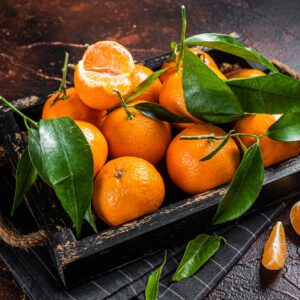 Fresh mandarin oranges or tangerines fruits with leaves. Dark background. Top view